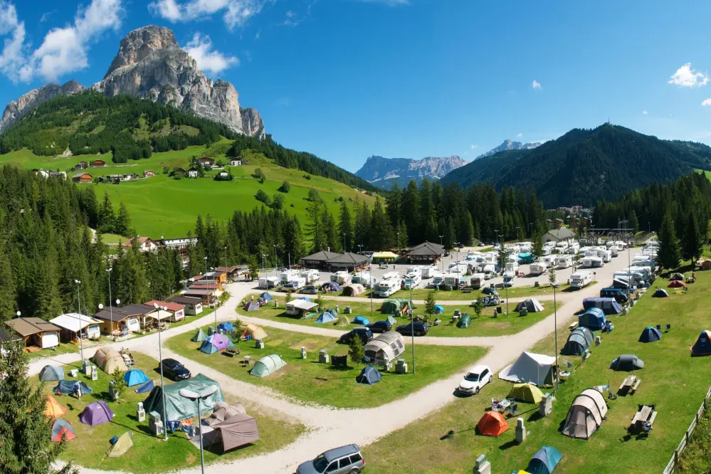 Panoramafoto mit den Stellplätzen und im Hintergrund die Dolomiten des Camping Colfosco in Alta Badia in Südtirol