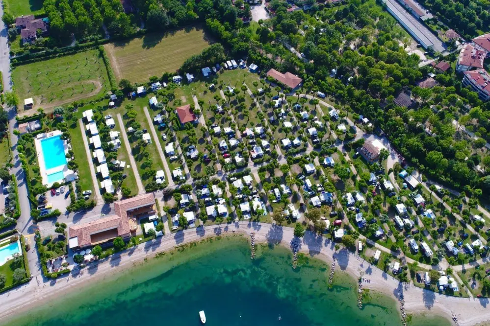 Panoramafoto mit Gardasee, Stellplätzen und Schwimmbad des Campingplatzes Ferienglück Rio