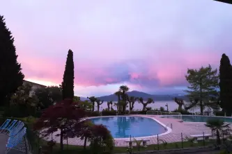 Foto bei Sonnenuntergang des Swimmingpools mit Blick auf den Gardasee auf dem Camping Sirmione