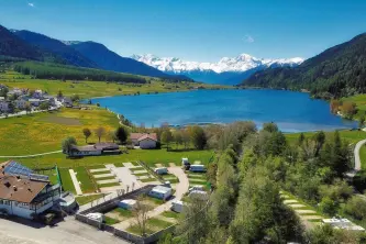 Panoramablick auf den Campingplatz Zum See mit dem See und den Dolomiten in Südtirol im Hintergrund