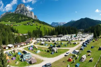 foto panoramica con le piazzole e sullo sfondo le dolomiti del camping colfosco in Alta Badia in Alto Adige